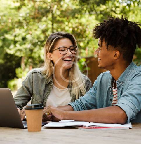 image-17-copyright.jpg Positive young multiethnic couple spending time together at the park, studying while sitting at the table with laptop